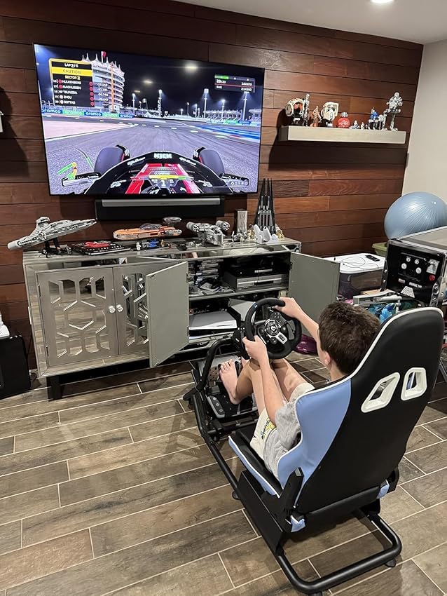 Immersive racing simulator setup with a large screen, steering wheel, pedals, and racing seat